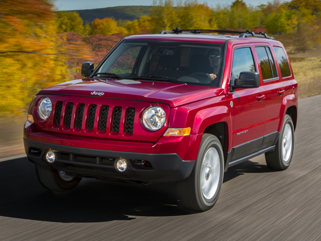 Jeep Patriot driving on a road with autumn trees in the background.