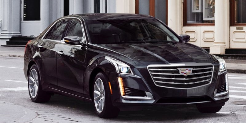 Black Cadillac sedan front view parked outside building