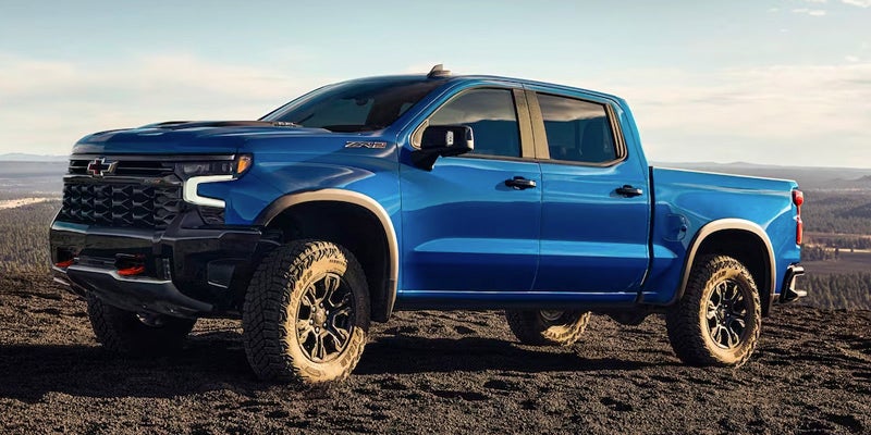 A blue Chevrolet Silverado ZR2 pickup truck parked on a rocky landscape with a valley and sky in the background.