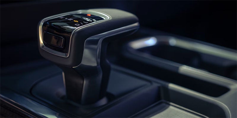 A sleek, dark car gear shifter with chrome accents, showing drive settings (P-R-N-D/L) and an illuminated 