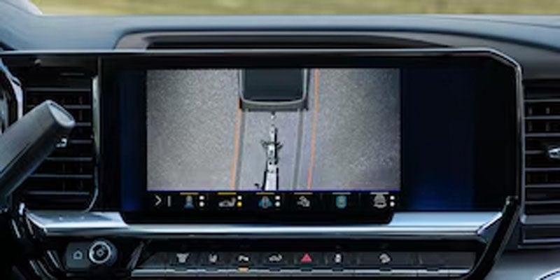 Dash view of a car's infotainment screen showing a top-down camera view of a truck backing up to a trailer.
