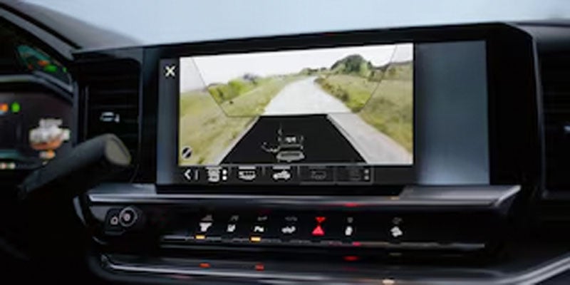 Vehicle dashboard with a large display showing a curved road ahead as seen from the backup camera.