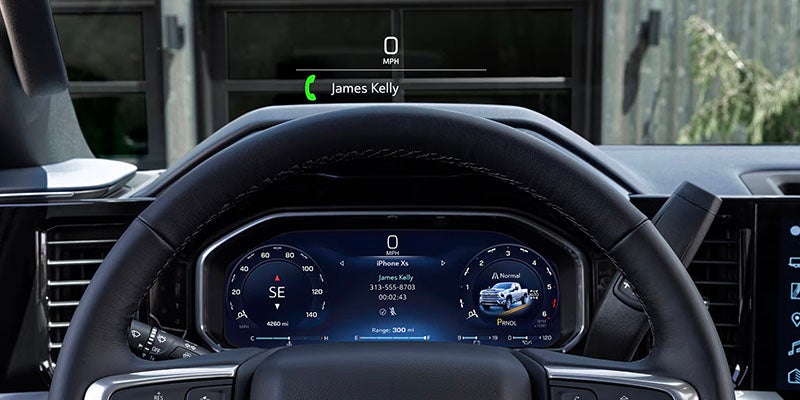A car steering wheel in view, with a digital display behind it showing navigation and an incoming call.
