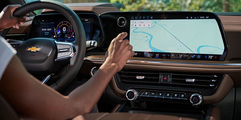 Vehicle interior showing steering wheel, digital dashboard, and large touchscreen navigation display.