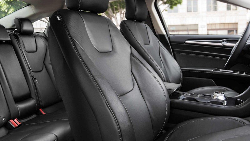 Modern car interior showcasing black leather seats with white stitching, backseats visible through the front passenger seat.