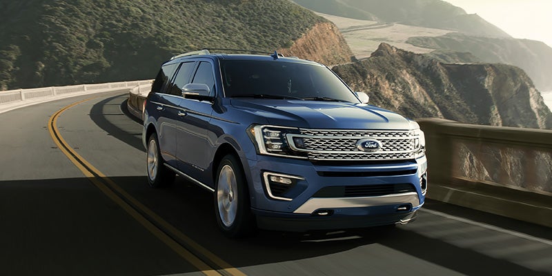 A blue Ford Expedition suv driving on a scenic road