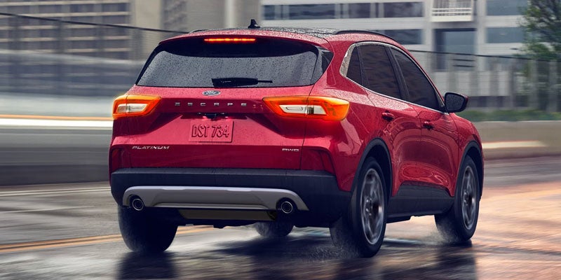 Ford Escape Platinum SUV driving on a wet road, with urban buildings in the background.