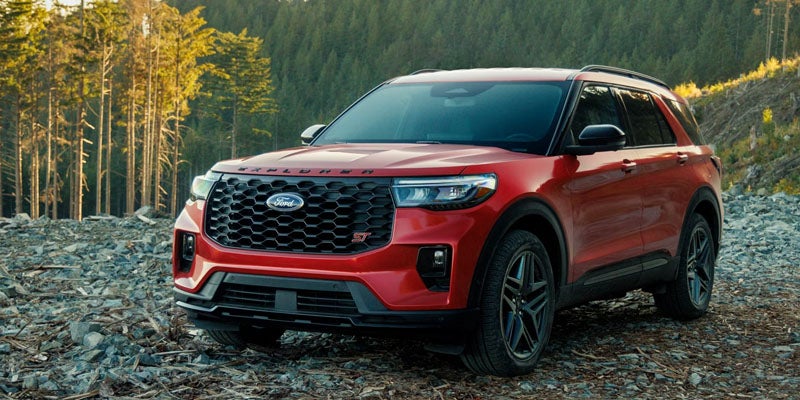 Ford Explorer ST SUV on a rocky mountain path with a forest in the background.