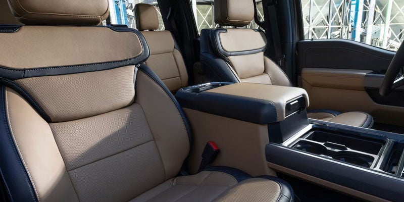 Interior view of a car with tan perforated leather seats and dark blue trim, center console visible.