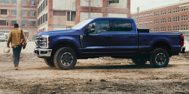 Ford F-250 Tremor pickup truck on a dirt lot with brick buildings in the background.