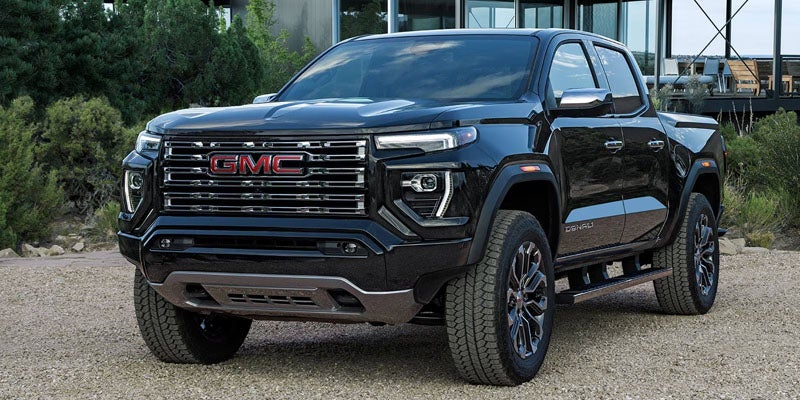 A black GMC Elevation pickup truck sits parked on a gravel surface, viewed from a low angle.