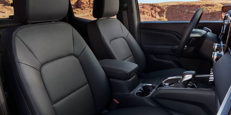 The interior of a black pickup truck shows two leather bucket seats and a dashboard.