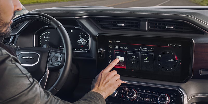 Man in a GMC Denali touching the Lights icon on the infotainment system
with a trailer connected.