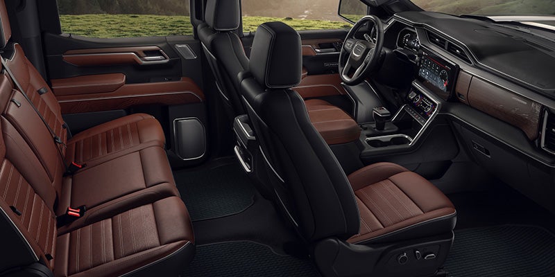 Interior of a truck cabin with brown leather seats and dark brown accents, featuring a large infotainment screen.