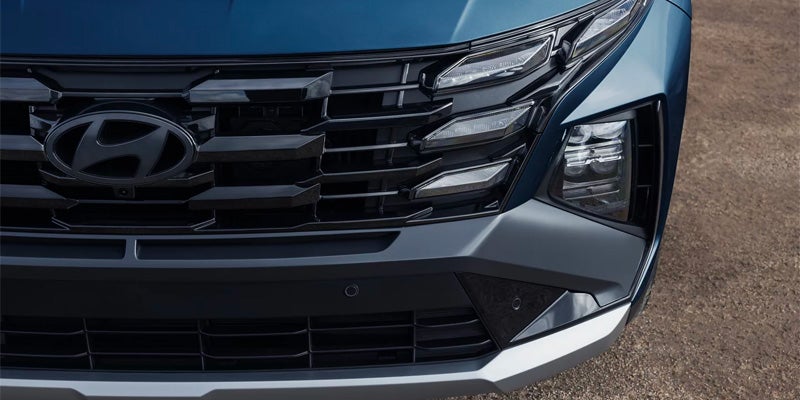 Front view close-up of a blue Hyundai car, showing the glossy black grille and daytime running lights.