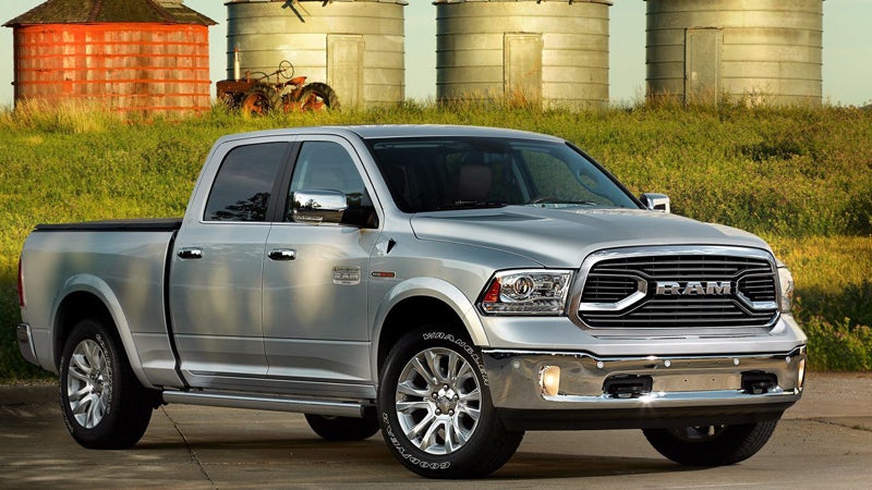 A silver Ram pickup truck parked on asphalt with a grassy field