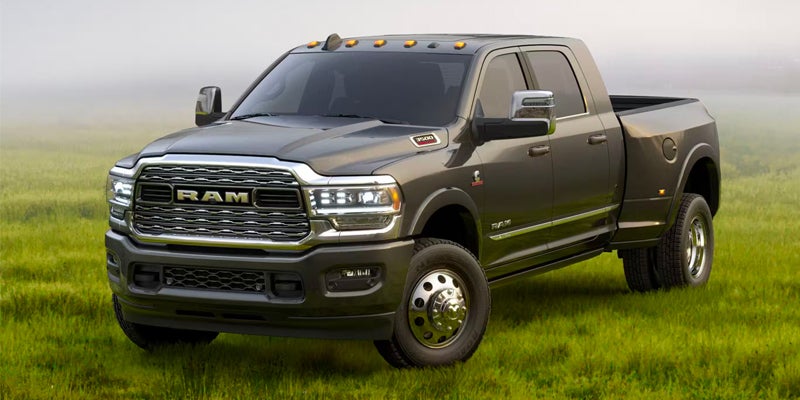 A dark gray Ram 3500 dually pickup truck parked in a grassy field with a foggy sky in the background.