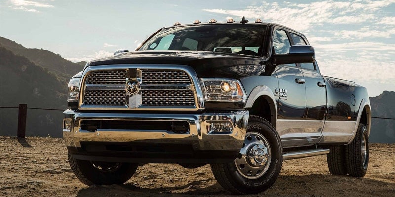 A black Ram 5500 heavy-duty pickup truck with a chrome grille and bumper is parked on a dirt road.