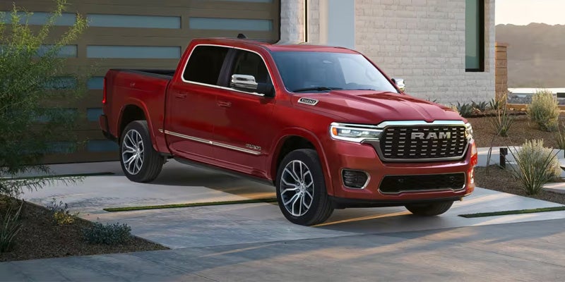 A red Ram pickup truck parked diagonally in a modern-style driveway, with a garage and desert landscaping.