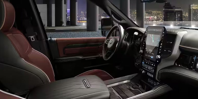 Ram Limited truck at night, with luxurious black and reddish-brown leather seats, and a large infotainment screen.