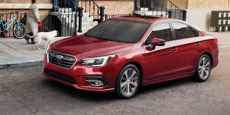 A red Subaru sedan parked on a city street
