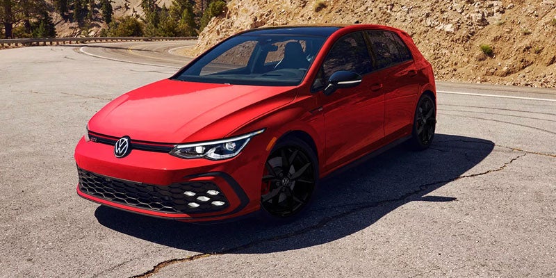 Red Volkswagen Golf GTI parked on a curved mountain road